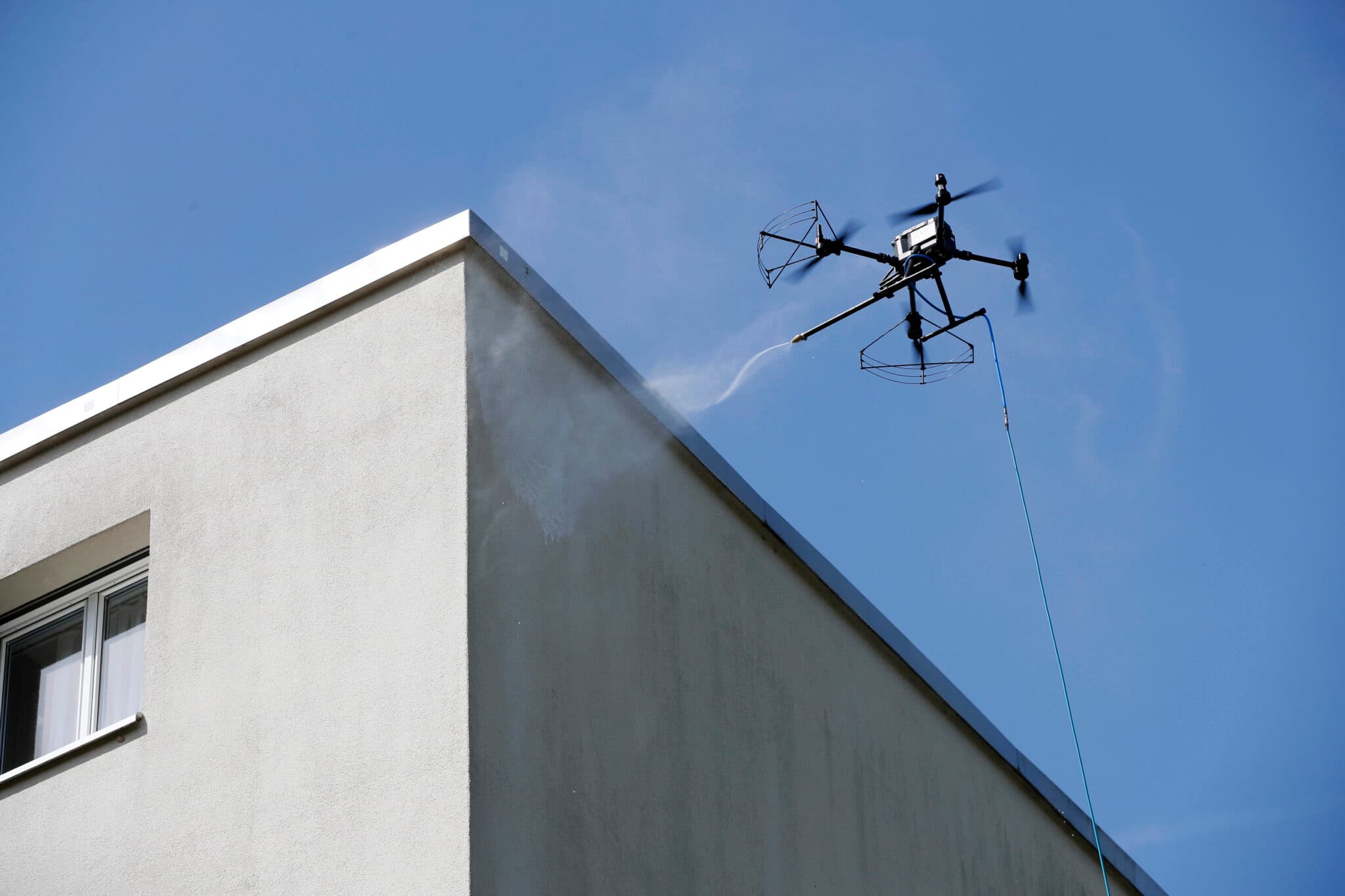 Drone applying cleaning solution to a commercial building facade